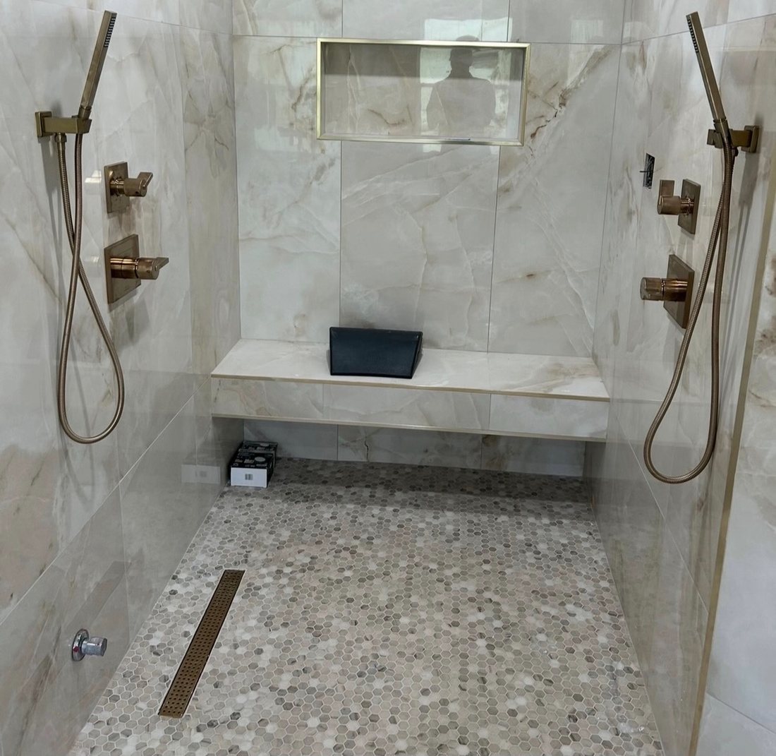 Custom marble walk-in shower with a built-in bench by Verano
